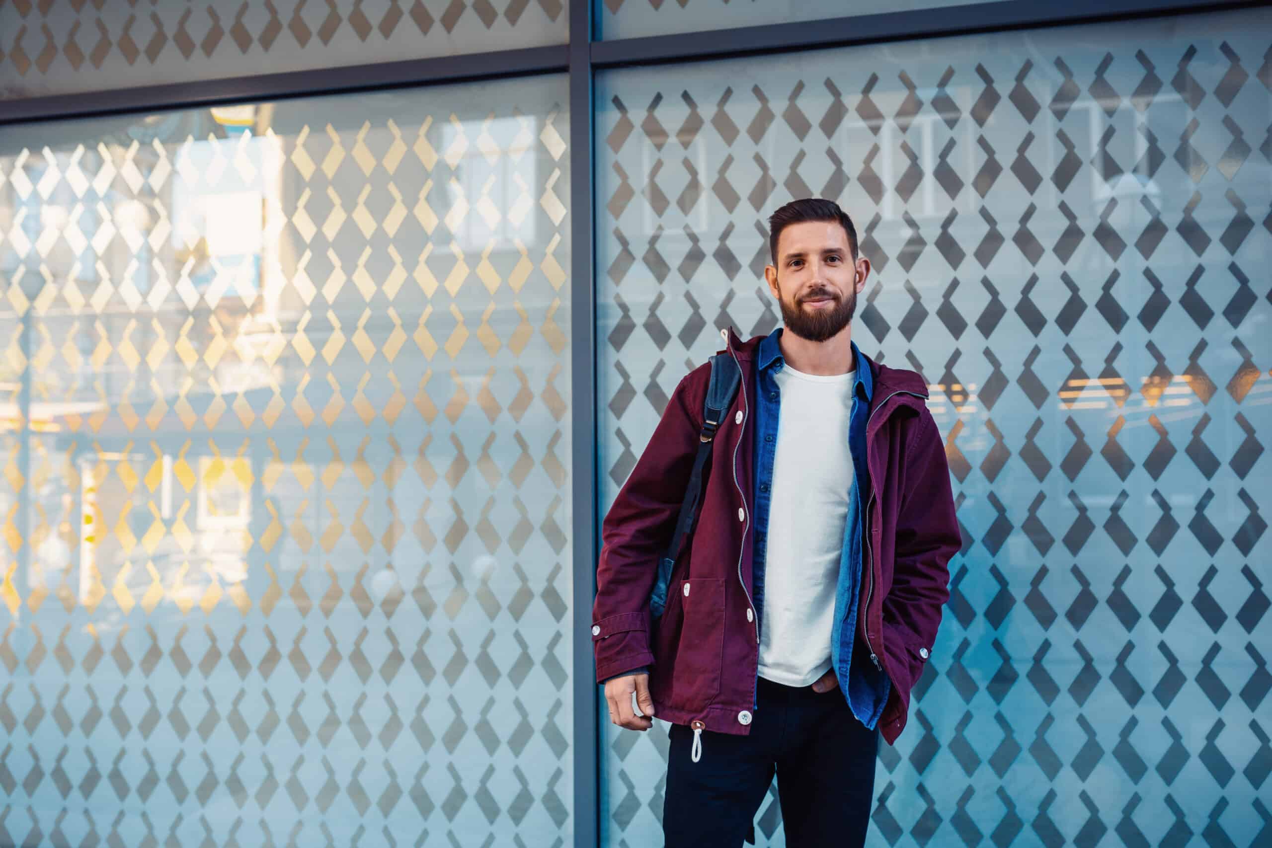 Durchfall und Antibiotika hängen oft zusammen: Mann mit lila Jacke steht vor Glasscheiben.